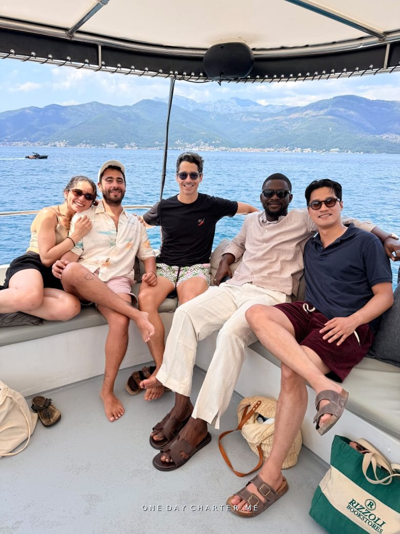 Friends relaxing in the shade on board with the mountains of the Bay of Kotor behind