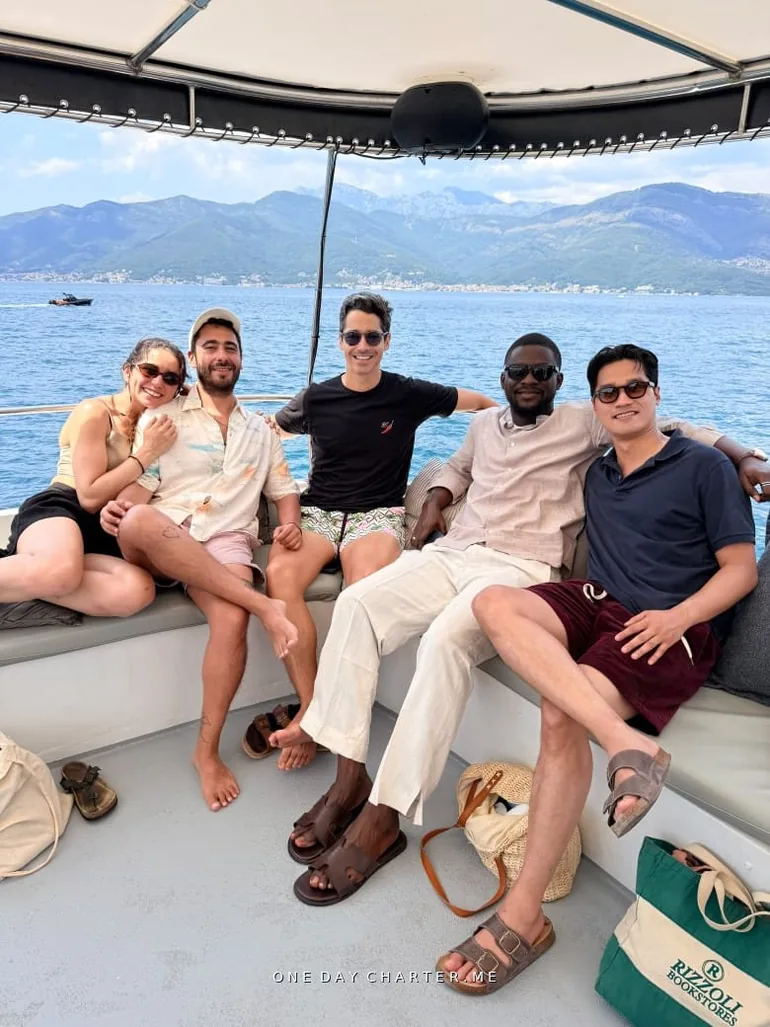 Friends relaxing in the shade on board with the mountains of the Bay of Kotor behind