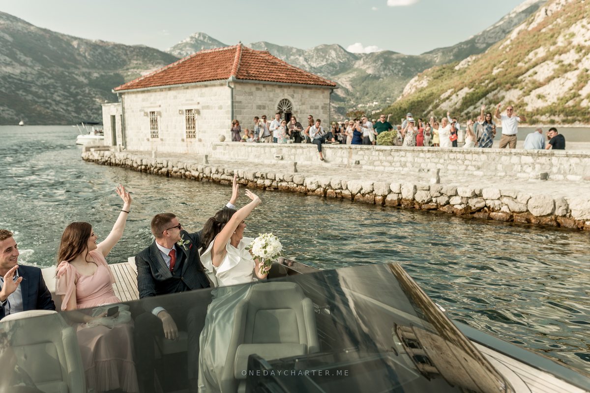 Leaving Our Lady of the Rocks by boat after the wedding, guests waving from the island